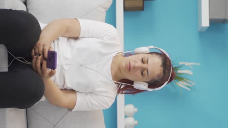 Vertical-video-of-Woman-listening-to-music-with-headphones-is-unhappy-and-sad.
